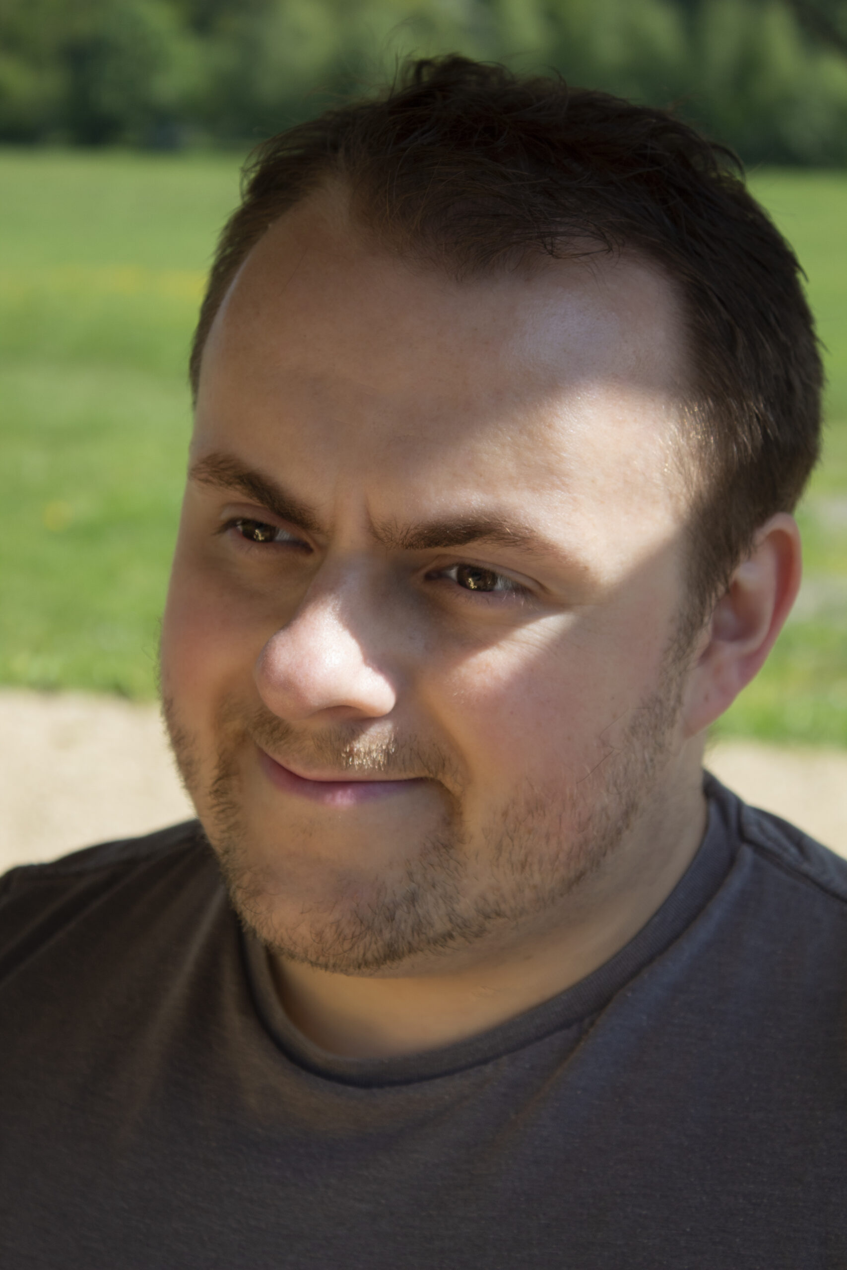 Close of Headshot of LGBT voice actor Jaden randall. Outside on a summers day in a field. 